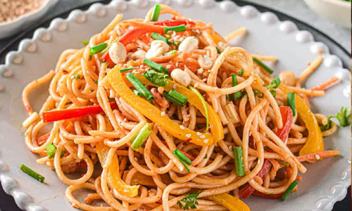 A bowl of Thai peanut noodles topped with crushed peanuts